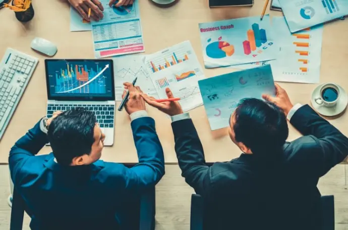 Team collaborating around a table with charts and graphs for business analytics.